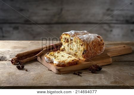 Christmas cake in germany christstollen with cinnamon sticks and anise stars on a rustic kitchen table wooden vintage background with copy space selected focus narrow depth of field