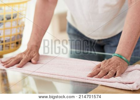 Hands of housewife folding clean clothes on laudry day