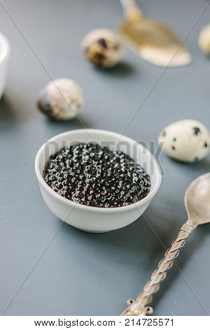 A black caviar in a white ceramic bowl.