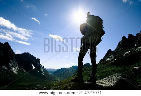 silhouette of woman with backpack hiking on sunrise mountain top