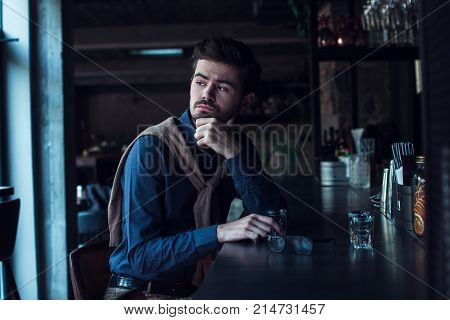 Where is she? Handsome young man looking away while sitting in loft interior at bar
counter