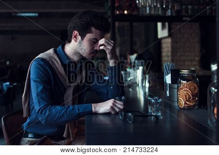 So tired today. Handsome young man looking tired and exhausted while sitting in loft
interior at bar counter