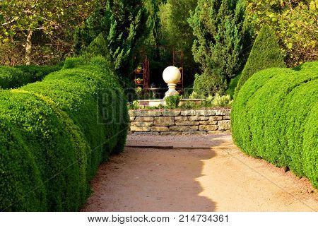 Walkway leading to a courtyard surrounded by manicured plants taken in a garden