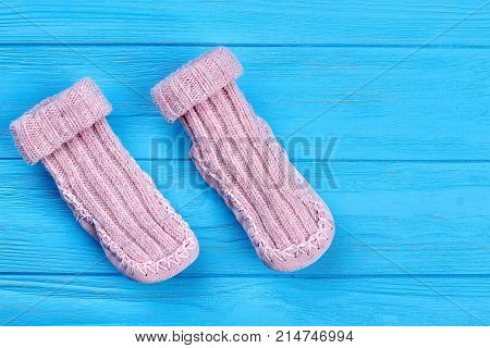 Baby wool socks on blue background. Pair of light pink baby-girl warm knitted socks on sale.