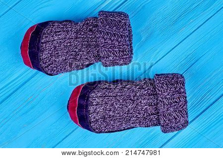 Woolen socks of handwork on blue background. Top view of warm wool knitted socks with textile soles on wooden background close up. Room wool slippers with leather soles.