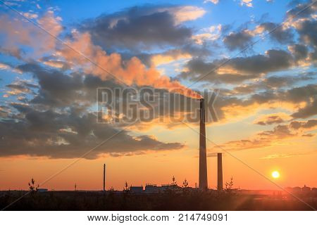 View of a smelter stack of a nickel plant showing the emission on the air with sunset sky as as background