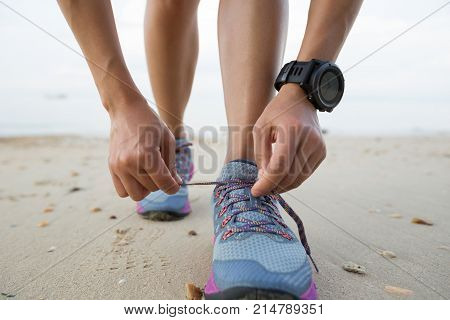 healthy lifestyle young fitness woman runner tying shoelace on beach