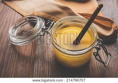 Desi Ghee or clarified butter in glass or Copper container or ceramic jar with spoon, selective focus