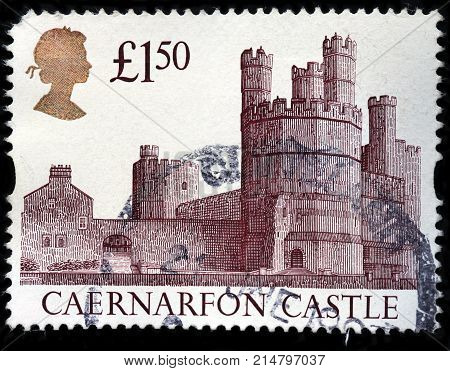 LUGA RUSSIA - AUGUST 20 2017: A stamp printed by GREAT BRITAIN shows portrait of Queen Elizabeth II against Caernarfon Castle - medieval fortress in Caernarfon Gwynedd Wales circa 1992