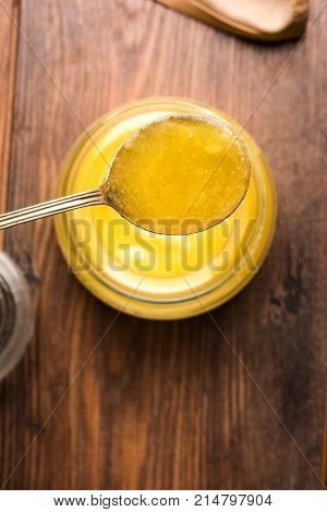 Desi Ghee or clarified butter in glass or Copper container or ceramic jar with spoon, selective focus