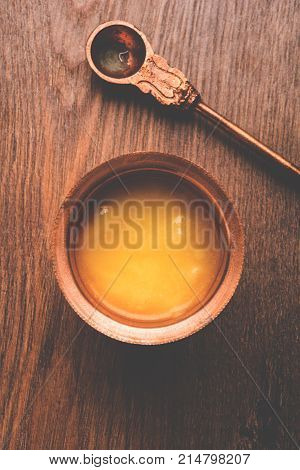 Desi Ghee or clarified butter in glass or Copper container or ceramic jar with spoon, selective focus