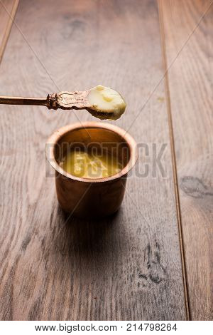 Desi Ghee or clarified butter in glass or Copper container or ceramic jar with spoon, selective focus