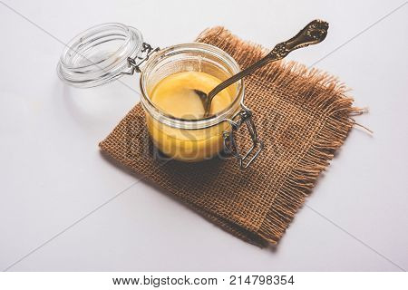 Desi Ghee or clarified butter in glass or Copper container or ceramic jar with spoon, selective focus