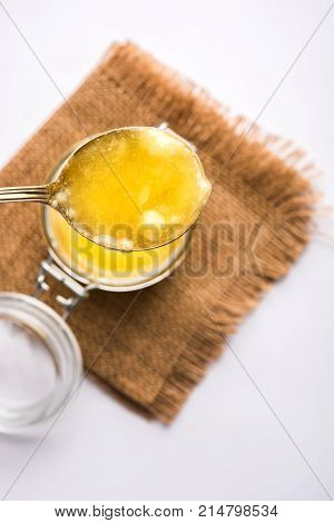 Desi Ghee or clarified butter in glass or Copper container or ceramic jar with spoon, selective focus