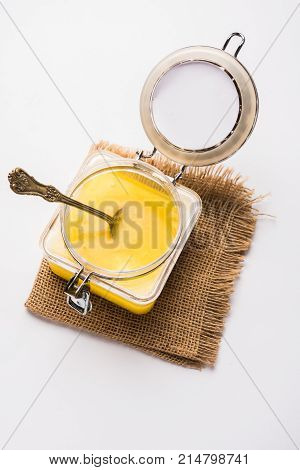 Desi Ghee or clarified butter in glass or Copper container or ceramic jar with spoon, selective focus