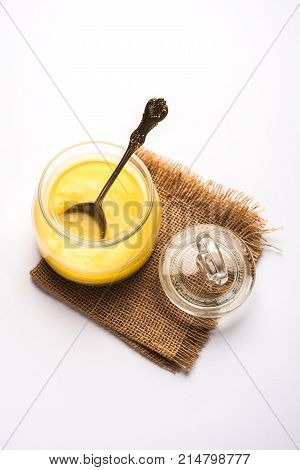 Desi Ghee or clarified butter in glass or Copper container or ceramic jar with spoon, selective focus