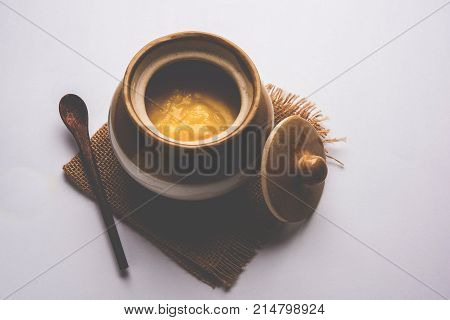 Desi Ghee or clarified butter in glass or Copper container or ceramic jar with spoon, selective focus
