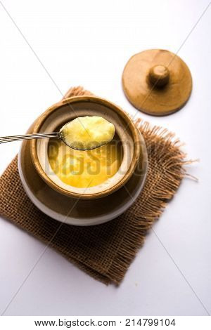 Desi Ghee or clarified butter in glass or Copper container or ceramic jar with spoon, selective focus