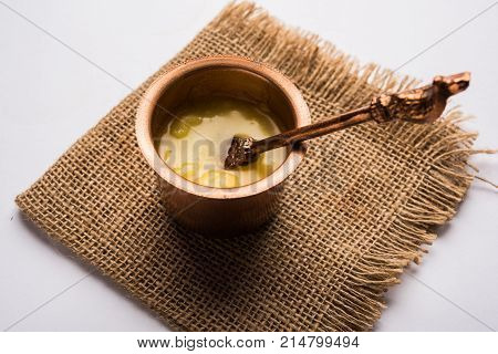 Desi Ghee or clarified butter in glass or Copper container or ceramic jar with spoon, selective focus