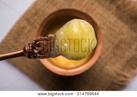Desi Ghee or clarified butter in glass or Copper container or ceramic jar with spoon, selective focus