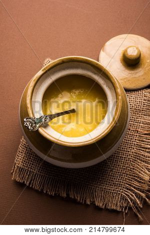 Desi Ghee or clarified butter in glass or Copper container or ceramic jar with spoon, selective focus