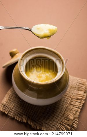 Desi Ghee or clarified butter in glass or Copper container or ceramic jar with spoon, selective focus