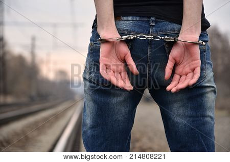 Girl In Handcuffs On The Background Of A Railway Track. The Concept Of Crime Prevention With The Par