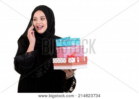 Happy young muslim woman with shopping bag and gift boxes isolated over white background.