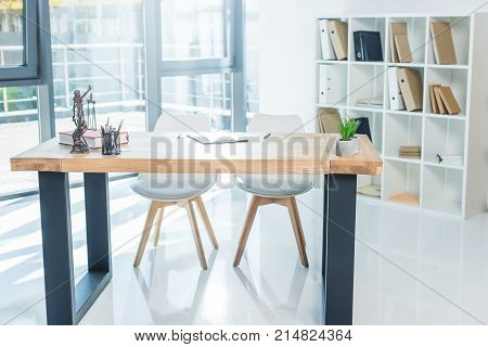 empty workplace with femida documents and book on table and bookshelf in office