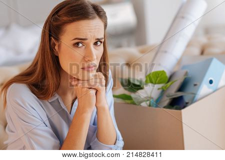 Dismissed woman. Beautiful young dismissed woman sitting with her head on the hands and feeling unhappy after being dismissed from work