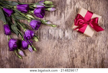 Gift box with bow and purple flowers. Eustoma. A romantic gift. Copy space
