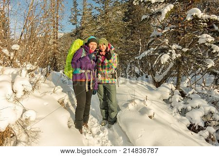 Two Happy Women Traveler With Backpacks Walking In Winter Forest