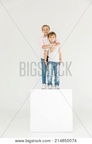 adorable happy siblings standing together and smiling at camera isolated on white
