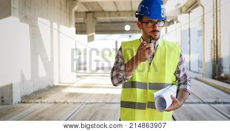 Male architect communicating on walkie-talkie at building site