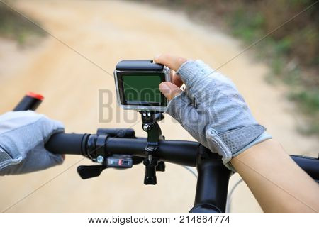 cyclist hands set the action camera mounted on mountain bike