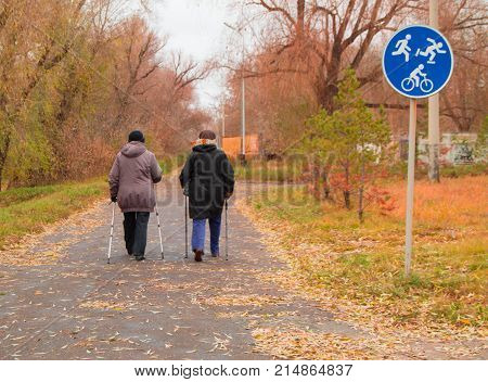 Nordic Walking For Two Elderly Women Outdoors In Autumn Park