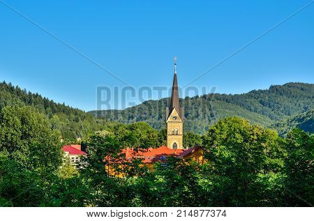 Mountain summer landscape. Church tower in the countryside on a background of beautiful green hills.