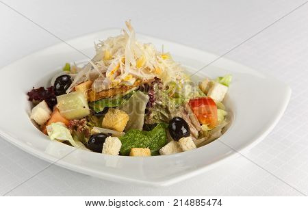 Chicken salad with tomatoes, olives, cheese and bread croutons on white background