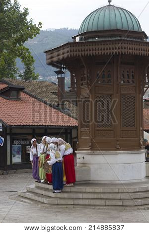 SARAJEVO, BOSNIA AND HERZEGOVINA - AUGUST 20 2017: Women wearing traditional Bosnian ethnic clothing in front of the Sebilj fountain on Bascarsija city centre