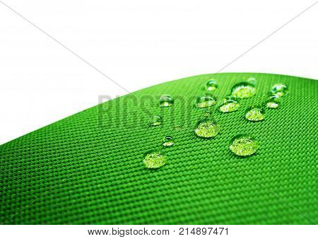 Green waterproof fabric with waterdrops close up on white background