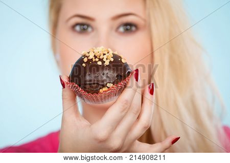 Diet sweets food concept. Woman holding delicious chocolate cupcake with peanut frosting about to take bite
