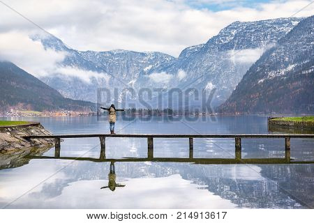 Woman enjoying alpine scenery - Holiday destinations theme image of a woman with open arms enjoying the lovely Hallstatter lake and the peaks of the Dachstein Mountains in Hallstatt Austria.