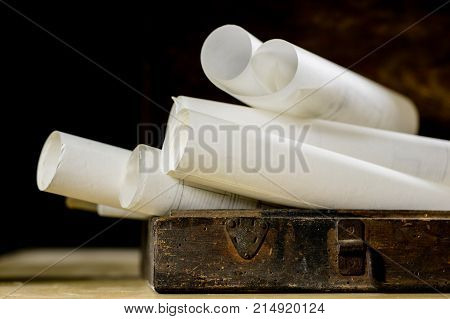 Old Rolls And Plans In Folded Paper Rolls. Old Book And Case. Documents On An Old Wooden Table.