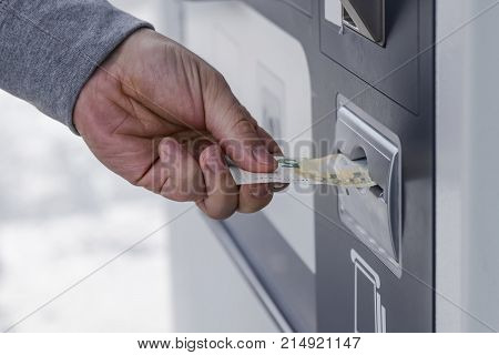 person's hand sticks a paper money bill into the banknote bill acceptor