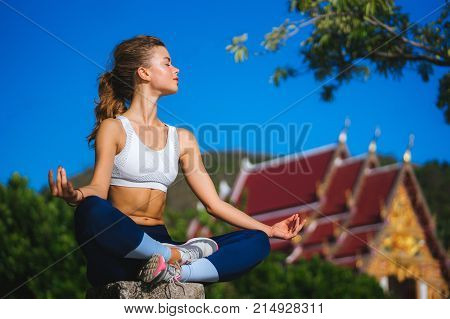 Girl in Lotus pose in the background of the temple. Buddhism. Yoga practice