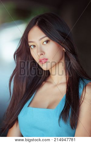 Woman portrait. Sensual lovely and beautiful mixed race asian caucasian young girl looking at camera outdoor against green blurred bokeh background. Gorgeous slim model posing outside