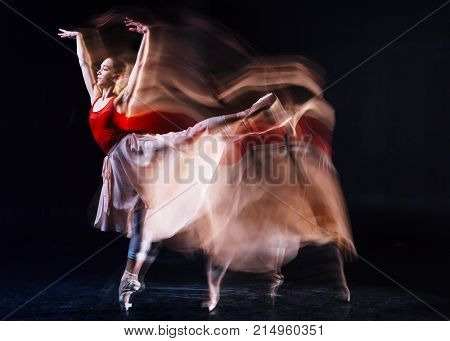 Professional ballet dancer. Skillful beautiful female dances raising her leg and looking in front of her while dancing ballet