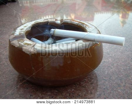 Smoking cigarette butt in the ashtray on the marble table