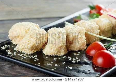 Close up of cheese rolls with sezam on a black plate served with cherry tomatoes copyspace restaurant menu delicious food eating appetizer hunger appetite cafe concept.