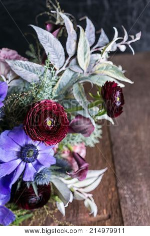 celebration, growing, flower arranging concept. close up of persian battercups that have leaves in colour of wine and sunny yellow centre, they are placed in the wedding bunch
